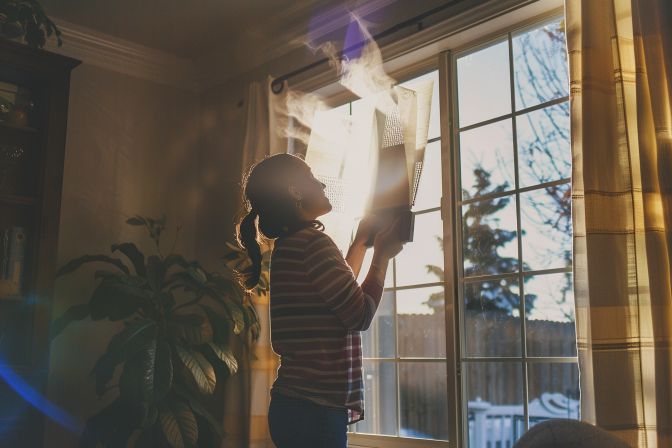 Homeowner changing dirty air filter in poorly lit room. Homeowner changing dirty air filter in poorly lit room.