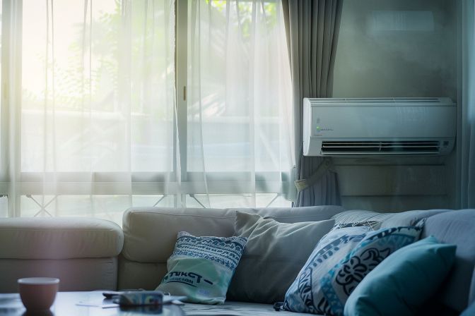 A well-used air conditioning unit in a cluttered living room. A well-used air conditioning unit in a cluttered living room.