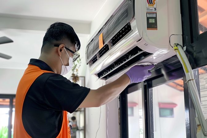 A technician conducting a thorough aircon chemical wash in a home.
