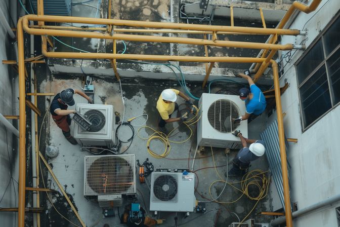 A busy maintenance team works on a dirty central air conditioning unit. A busy maintenance team works on a dirty central air conditioning unit.