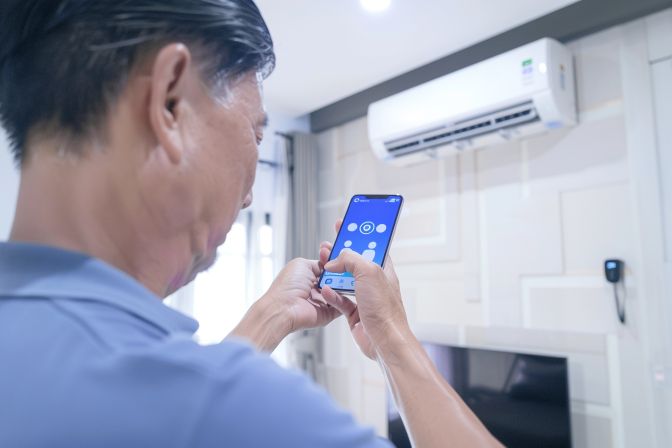 A man sets up smart air conditioning with Google Home in 2021. A man sets up smart air conditioning with Google Home in 2021.