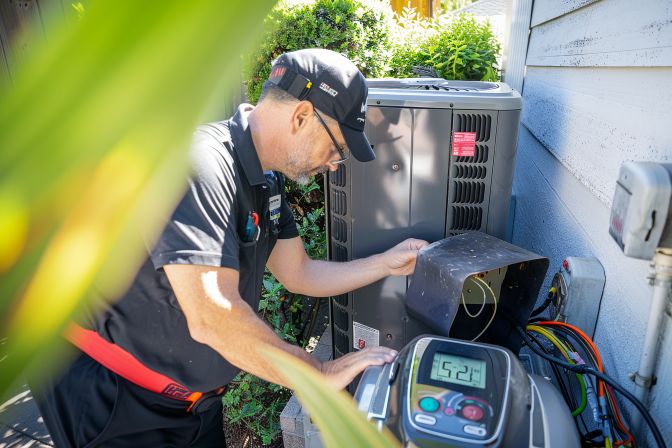 A technician checks an air conditioning unit for low refrigerant levels. A technician checks an air conditioning unit for low refrigerant levels.