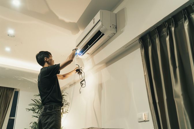 A technician conducting routine maintenance on a residential air conditioning unit. A technician conducting routine maintenance on a residential air conditioning unit.
