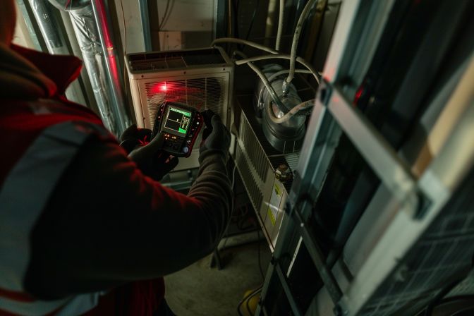 A technician checks an air conditioning unit for early signs of problems. A technician checks an air conditioning unit for early signs of problems.