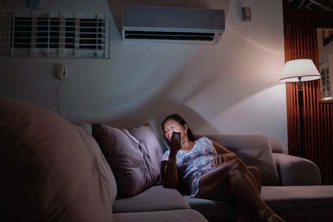 A frustrated woman struggles to operate her aircon remote at home. A frustrated woman struggles to operate her aircon remote at home.