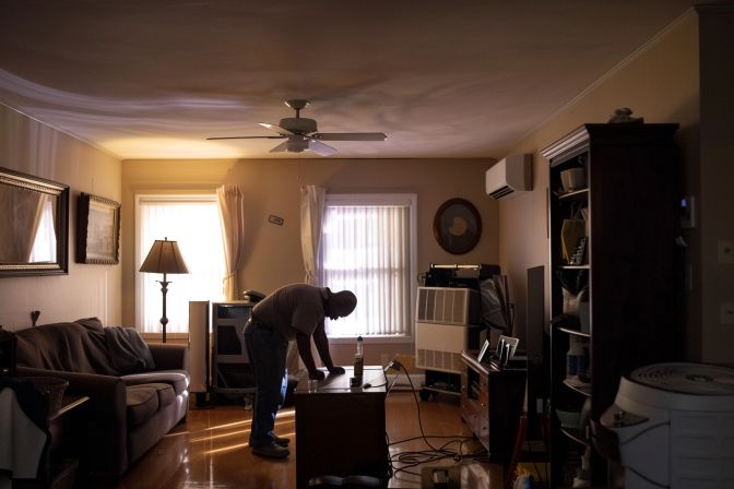 A technician servicing an air conditioning unit in a residential living room. A technician servicing an air conditioning unit in a residential living room.